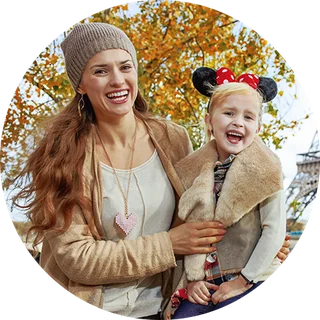 A mother and her young daughter in Minnie ears, smiling together outdoors