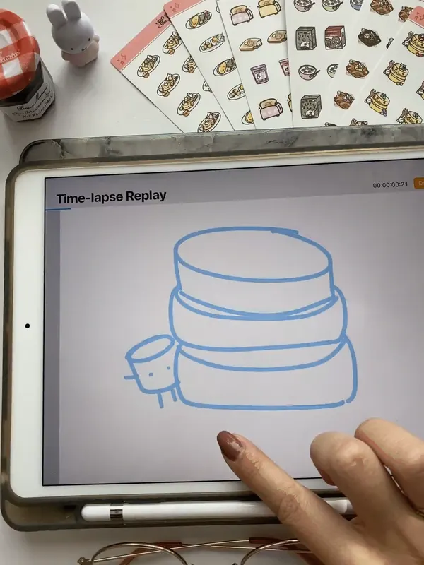 Time-lapse of a stack of pancakes with blueberries being drawn on an iPad, with Paper and Milk sticker sheets on the desk behind it